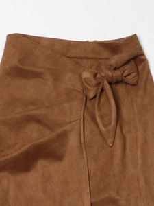 Detailed view of the bow-knot waist tie and faux suede texture on a brown midi skirt