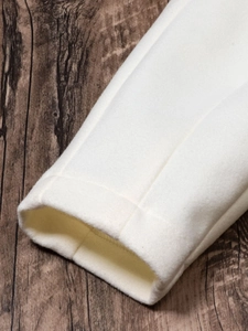 Close-up of the premium stitched cuffs on a cream-colored minimalist French style blazer