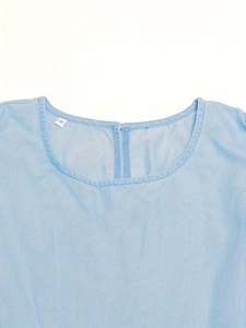Detail of round neckline and fabric texture on a light blue denim dress showing size S tag