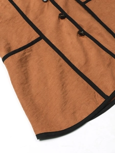 Detail of tan hooded jacket showing textured fabric, black piping and dark brown buttons