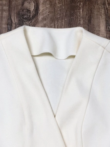 Macro shot of minimalist white V-neck blazer collar with premium textured fabric detail