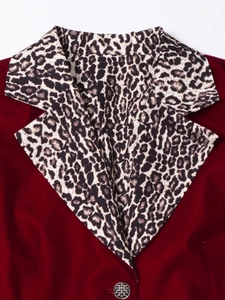 Detailed close-up of velvet blazer with leopard print lapel and textured metal button