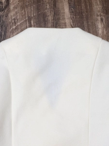 Macro shot of white wool-like blazer fabric showing premium texture and stitching details