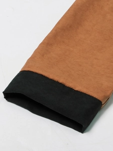 Detail of color-block cuff with brown fabric and black trim on long sleeve jacket