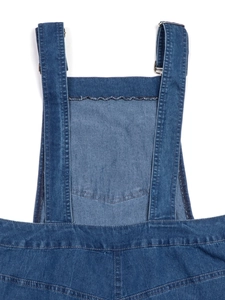 Detail of blue denim dress with adjustable shoulder straps and metallic silver buckles