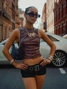 Detail of Y2K street style outfit with faux leather shorts and chunky gold diva necklace