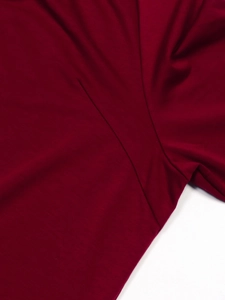Detailed close-up showing reinforced underarm stitching on a burgundy knit fabric shirt