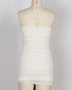Detail of white backless halter dress showing ruched elastic fabric and tie-back design