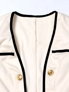 Women's cream-colored tweed blazer with black contrast trim and gold relief buttons