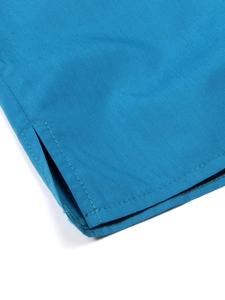 Détail de l'ourlet fendu sur chemise en coton bleu avec doubles coutures précises