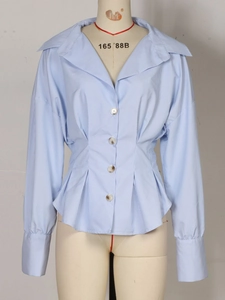 Détail d'un chemisier rayé bleu clair avec boutons marbrés et plis à la taille