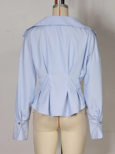 Détail du dos de la chemise rayée bleue avec des plis à la taille et grand col