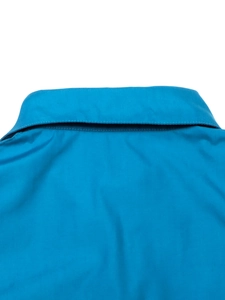 Détail du col de la chemise en coton bleu vif et des coutures précises sur les épaules