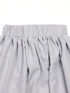 Détail de jupe taille haute gris clair avec ceinture élastique et plis en satin