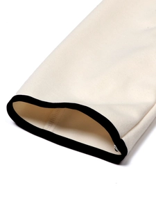 Detailed close-up of cream knit fabric with black piping trim on the sleeve cuff
