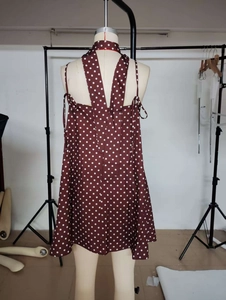 Detailansicht eines dunkelbraunen Polka-Dot-Neckholder-Kleides mit ausgestelltem A-Linien-Saum