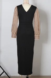 Detail of puff sleeves with striped pattern and gold buttons on a slim black maxi dress