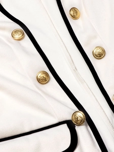 Detailed macro of gold vintage embossed buttons on white tweed blazer sleeve with black trim