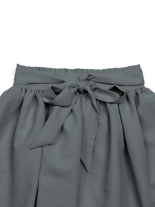 Détail d'une jupe grise à taille haute avec taille élastique plissée et ceinture à nœud chic