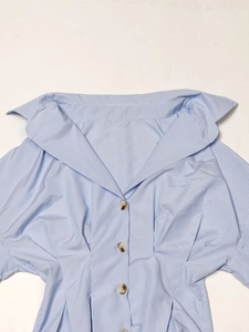 Détail d'une chemise à rayures bleues et blanches avec large col et boutons en écaille