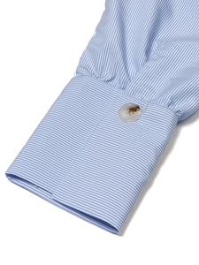 Vue rapprochée du poignet de chemise à rayures bleues et blanches et bouton nacré