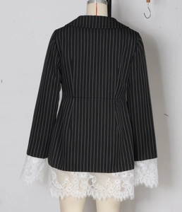 Detail of white eyelash lace stitching on the hem of a black pinstripe blazer dress