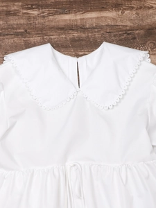 Women's white long sleeve blouse featuring a lace Peter Pan collar on dark wood background