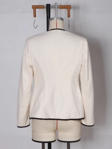 Back view of a white cropped blazer with black contrast trim on a mannequin stand