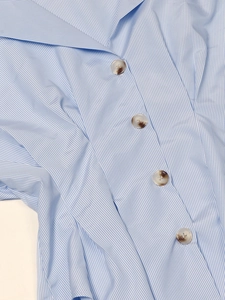 Détail du col d'une chemise à rayures bleues et blanches avec boutons marbrés