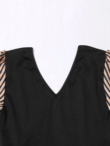 Detail view of a V-neck black dress with striped puff sleeves and a slim waist fit