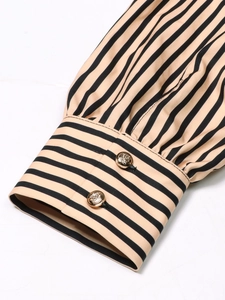 Slim fit V-neck dress featuring striped beige and black fabric with ornate gold buttons