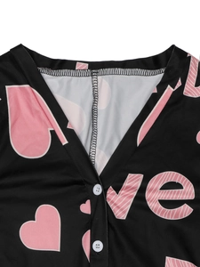 Close-up of V-neckline with pink hearts, love prints and white buttons on a black romper