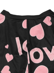 Detail showing pink heart and LOVE prints on black knit fabric of the slim jumpsuit