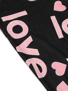 Detail of pink LOVE text and heart print on black slim fit jumpsuit fabric texture