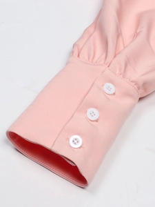 Elegant pink long sleeve dress with wide cuffs featuring three decorative white buttons