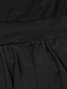 Detail of mesh stitching, solid waist belt and pleated hem on a black mini dress