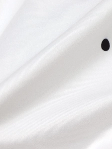 Detailed close-up of white satin fabric with classic black polka dots and twill texture