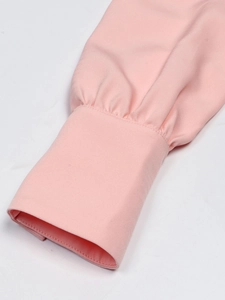 Detailed close-up of pleated cuff design and soft pastel pink fabric on women's dress