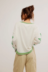 Détail du sweat-shirt à manches longues crème avec bordures vertes à cru sur le col et le dos