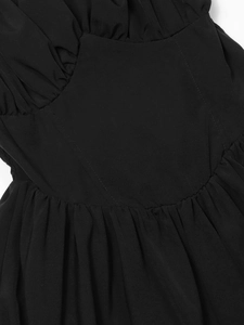 Detail der schwarzen Kleid-Taille mit V-Nähten und feiner, geraffter Textur am Stoff