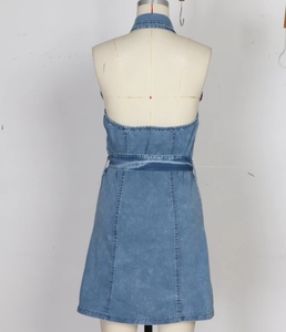 Detail of light blue denim halter dress featuring an open back and waist tie closure