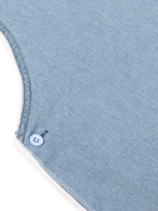 Detailansicht des Jeanskleids mit feinen Nähten und Knopf auf hellblauem Stoff