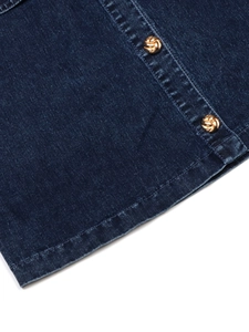 Détail d'une robe en jean bleu foncé avec boutons dorés texturés et coutures soignées