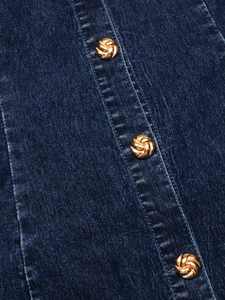 Gros plan sur la texture denim bleu foncé avec trois boutons métalliques dorés à spirale