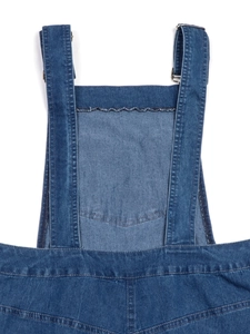 Detail view of dark blue denim overalls featuring adjustable metal buckles and straps