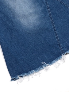 Detailed close-up of raw hem edge and washed blue denim texture on a long skirt
