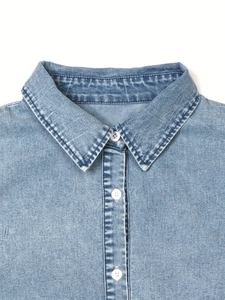 Detail view of light blue washed denim collar with white buttons and clean stitching