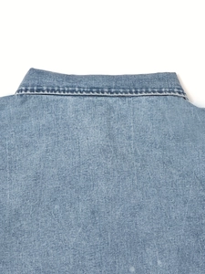 Detailed macro view of the turn-down collar and stitching on blue denim dress