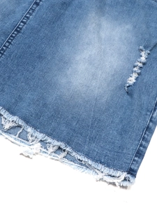 Detailed macro view of denim dress hem with distressed rips and raw frayed edges
