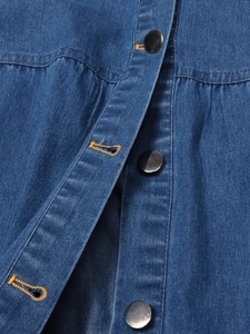 Close-up of blue denim dress showing contrast yellow stitching and metallic buttons